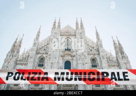 Nastro di polizia con l'iscrizione polizia Municipale sullo sfondo del Duamo di Milano. Il concetto di vietare le visite ai luoghi pubblici durante l'epidemia o pandemia del coronavirus COVID-19 Foto Stock