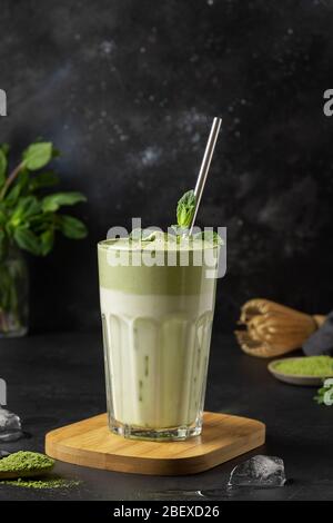 Bicchiere di tè Dalgona Iced Matcha. Latte freddo e tè pancha montato con uova bianche su fondo nero. Gustosa bevanda virale nel tempo autoisolamento. Vert Foto Stock