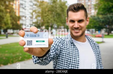Uomo che mostra un passaporto sanitario che indica che è immune al coronavirus Foto Stock
