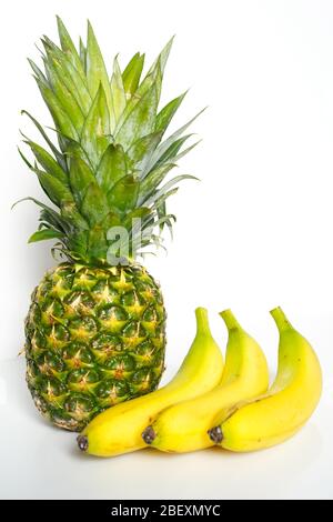 Un ananas intero e tre banane su uno sfondo bianco Foto Stock