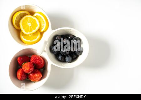 Un piatto da portata con limoni, fragole e uva nera a fette in ogni segmento Foto Stock