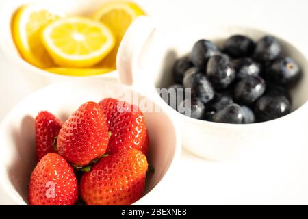 Un piatto da portata con limoni, fragole e uva nera a fette in ogni segmento Foto Stock