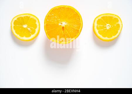 Due fette di limone e una fetta di arancia disposte in fila su uno sfondo bianco Foto Stock