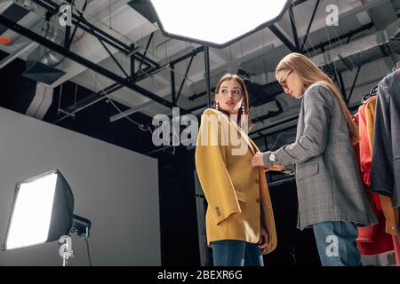 stilista in occhiali in piedi con bellissimo modello in studio fotografico Foto Stock