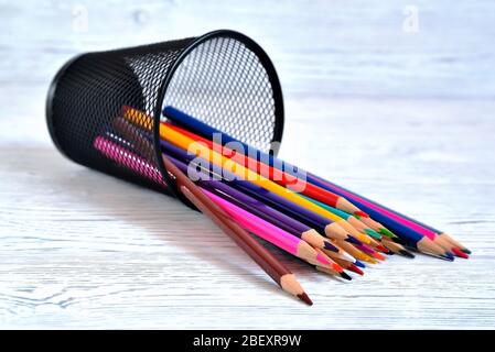 Molte matite multicolore in vetro a rete su uno sfondo naturale chiaro non uniforme Foto Stock