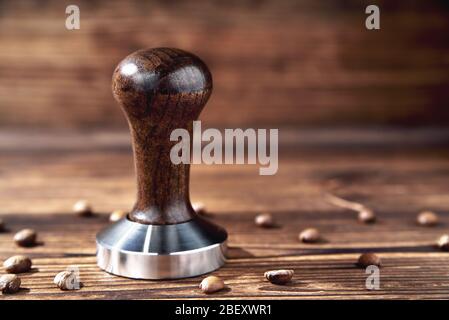 temperare i chicchi di caffè su uno sfondo di legno marrone sfocato Foto Stock