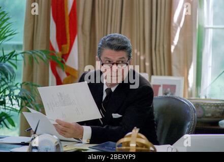 5/6/1982 il presidente Reagan con gli occhiali mentre si lavora alla sua scrivania in ufficio ovale Foto Stock