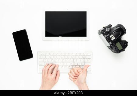 le mani delle donne che usano una tastiera e i pollici si alzano. Oggetti tecnologici, tablet, fotocamera, smartphone Foto Stock