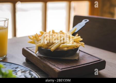 Patatine fritte in padella su tavolo di legno Foto Stock