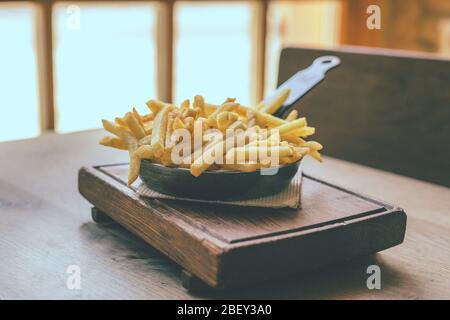 Patatine fritte in padella su tavolo di legno Foto Stock