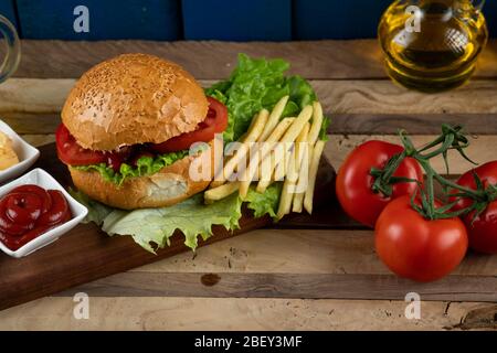 Hamburger, involtini di cipolle e patate fritte con salse e pomodori Foto Stock