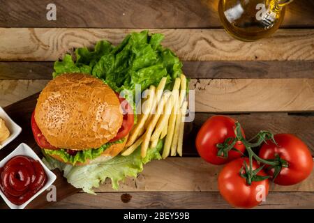 Hamburger, panini di cipolla e patate fritte con salse e pomodori, vista dall'alto Foto Stock