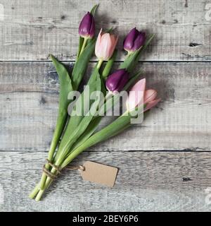 Rosa e tulipani viola legati con stringa e con un tag regalo in bianco Foto Stock