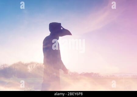 Una doppia esposizione di un personaggio con cappuccio e moody con una maschera medico peste, silhouette contro il tramonto. Con un sogno astratto e sperimentale come edit. Foto Stock