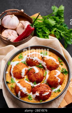 Malai Kofta Curry in ciotola nera. Il Malai Kofta è un piatto di cucina indiana con patate e formaggio paneer, polpette fritte in salsa di pomodoro e spezie. Foto Stock