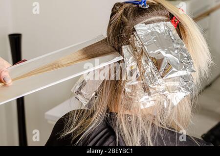 Set di tintura capelli. Polvere sbiancante applicata sui capelli e avvolgente nel foglio. Tecnica Air Touch. Fase 1 Foto Stock