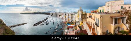 Vista della splendida Procida in estate soleggiata. Case colorate, caffè e ristoranti, barche da pesca e yacht a Marina Corricella, Foto Stock