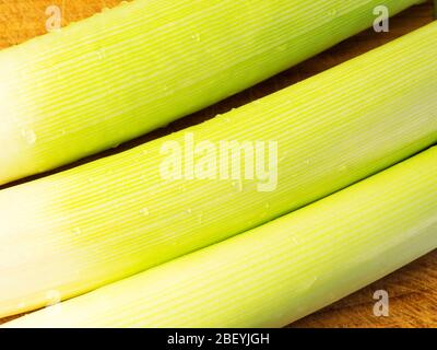 Tre porri freschi lavati su un tagliere di legno Foto Stock