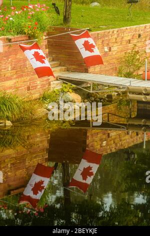 Bandiere canadesi riflesse nel fiume Wanapitei, Greater Sudbury, Ontario, Canada Foto Stock
