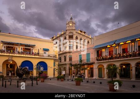I turisti che si siedono in prima serata si godono cenare fuori in ristoranti e caffè in Plaza Vieja, la città vecchia di Havana, Cuba Foto Stock