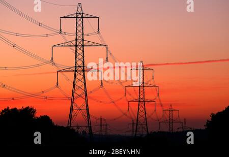 Fila di piloni elettrici al tramonto. Foto Stock