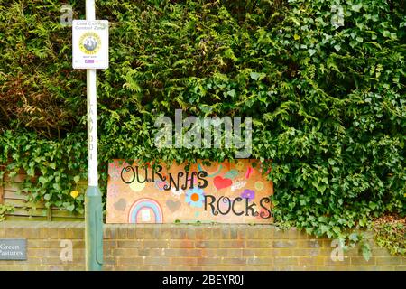 16 Aprile 2020, Southborough, Kent, UK: Disegni di un bambino di un arcobaleno, cuori e il nostro NHS Rocks messaggio per il personale NHS e lavoratori chiave su un pannello di compensato al di fuori di una siepe in zona residenziale durante il governo ha imposto quarantena / blocco per ridurre la diffusione del coronavirus. I bambini di tutto il paese hanno messo i disegni di arcobaleni nelle finestre per diffondere la speranza e incoraggiare la gente a rimanere allegra durante la pandemia. Foto Stock