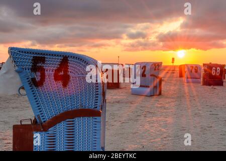 Sedie da spiaggia in vimini alla spiaggia di Neuharlingersiel al tramonto, Frisia orientale, bassa Sassonia, Germania Foto Stock