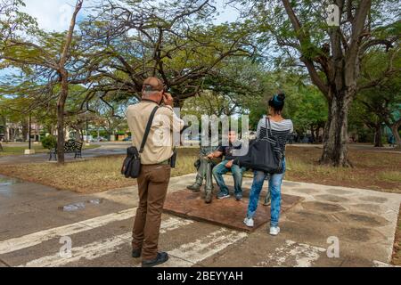 Turismo cubano - Boy con la sua foto scattata sul banco di John Lennon Square, l'Avana, Cuba Foto Stock