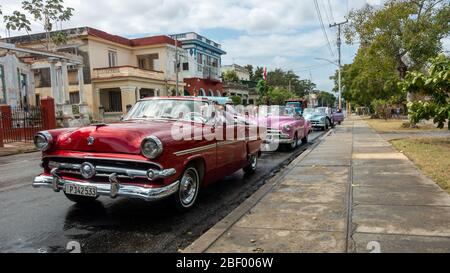 Linea colorata di taxi americani d'epoca con i turisti dopo aver visitato piazza John Lennon sulla calle 17, l'Avana, Cuba Foto Stock