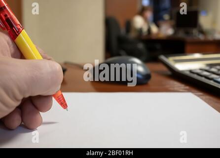 vista di una penna per scrivere davanti a un foglio bianco di carta nelle mani di un dipendente sullo sfondo dei lavoratori in ufficio Foto Stock
