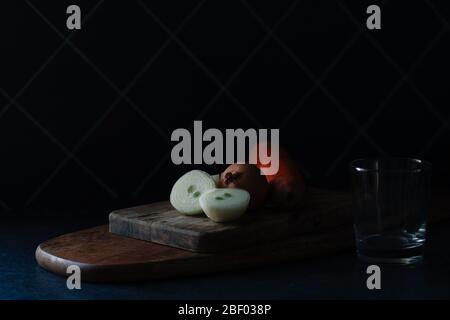 verdure prima di cucinare, cipolle, carote su un tagliando asse di legno. low key. primo piano Foto Stock