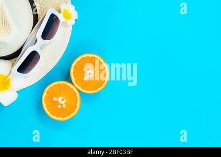 Bella vacanza estiva, accessori da spiaggia, occhiali da sole, cappello e arancione su sfondi blu Foto Stock