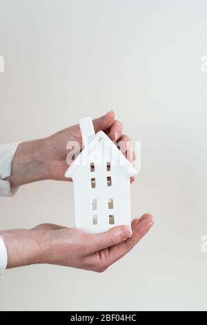 Una nuova casa in miniatura bianca in mano Foto Stock