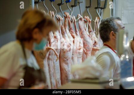 Bucarest, Romania - 16 aprile 2020: Carcassa di agnello appesa da ganci di ferro per la vendita in un macellaio rumeno prima di Pasqua. Foto Stock