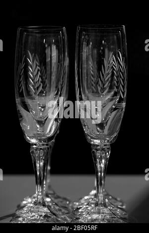 Bicchieri di champagne in cristallo, illuminati in camera oscura. Foto Stock