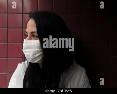 Bella giovane donna adulta che indossa maschera bianca per proteggere contro le malattie respiratorie e covide Foto Stock