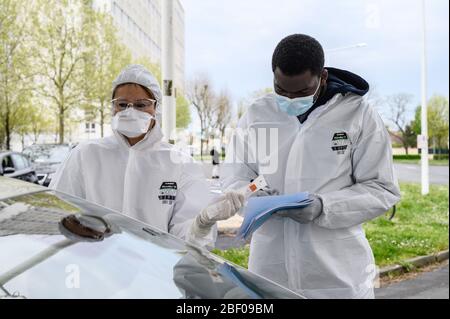 La Rochelle (Francia occidentale): Test di screening del coronavirus il 7 aprile 2020. Medico in tuta protettiva che preleva campioni da un autista a un Coro drive-thru Foto Stock