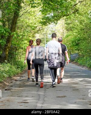 Kidderminster, Regno Unito. 16 aprile 2020. Con il Regno Unito nella sua quarta settimana di blocco a causa del coronavirus, la gente sta mantenendo i loro spiriti in su e mentre il sole continua a brillare si assicurano ancora stanno ottenendo fuori per esercitarsi una volta al giorno. Questa famiglia britannica, catturata da dietro, fa una passeggiata a piedi lungo una tranquilla strada di campagna. Credito: Lee Hudson Foto Stock