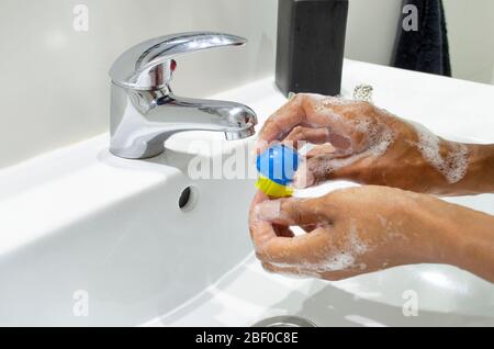 Donna nera che lava coscienziosamente le mani con sapone e pulendo le unghie con una spazzola. Messa a fuoco selettiva sulle mani. Disinfezione. Concetto di igiene. Foto Stock