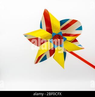 Una vista ravvicinata di un tradizionale giocattolo a vento in plastica per bambini con uno sfondo patriottico di Union Jack in rosso, bianco e blu e oro scintillante Foto Stock