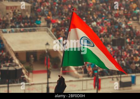Una persona che alza la bandiera indiana al confine di Wagha in Amritsar, Punjab. Foto Stock