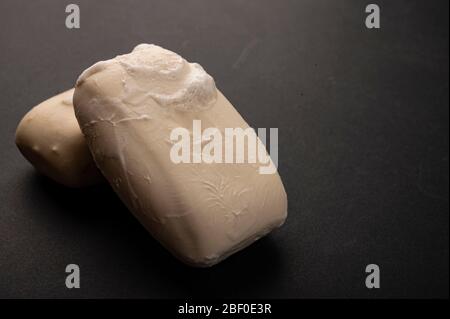 Due pezzi di sapone da toletta su fondo nero. Primo piano. Il rispetto delle norme di igiene personale è la prevenzione dell'infezione da COVID-19 Foto Stock