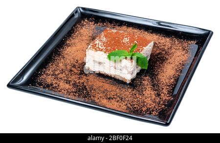 torta tiramisù su piatto nero. gustoso dessert italiano decorato con menta Foto Stock