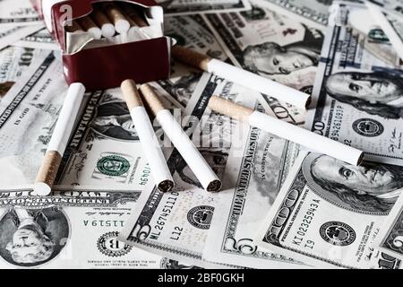 Concetto di costo del fumo. Cigarete su un fondo di dollari. Foto Stock