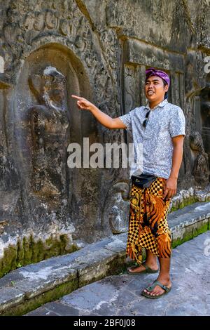 Ritratto verticale di una guida turistica locale a Yeh Pulu Relief a Bali, Indonesia. Foto Stock