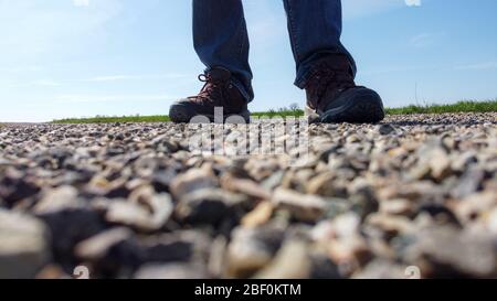 Le gambe di un uomo in sneakers si trovano su una strada di ghiaia Foto Stock