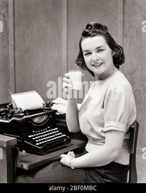 1930S BRUNETTE DONNA SEGRETARIO SEDUTO A MACCHINA DA SCRIVERE GIRATA GUARDANDO LA FOTOCAMERA TENENDO UN BICCHIERE DI LATTE SORRIDENTE PAGEBOY HAIRSTYLE - F1146 HAR001 HARS GIOIA LIFESTYLE SODDISFAZIONE CHIERK DONNE LAVORI HEALTHINESS LATTICINI COPIA SPAZIO METÀ LUNGHEZZA DONNE PERSONE PROFESSIONE FIDUCIA B&W CONTATTO OCCHI BRUNETTE ABILITÀ OCCUPAZIONE FELICITÀ ALLEGRA BEVANDA MANUALE CARRIERE FLUIDO HAIRSTYLE UFFICIO OCCUPAZIONI SORRIDENTI GIRATI GAL VENERDÌ ANCORA VITA AMMINISTRATORE GIOIOSO SEGRETARI ELEGANTE AMANUENSIS PAGEBOY PROTEINA GIOVANE DONNA ADULTA BEVANDE BIANCHE E NERE ETNIA CAUCASICA CLERICALE HAR001 Foto Stock