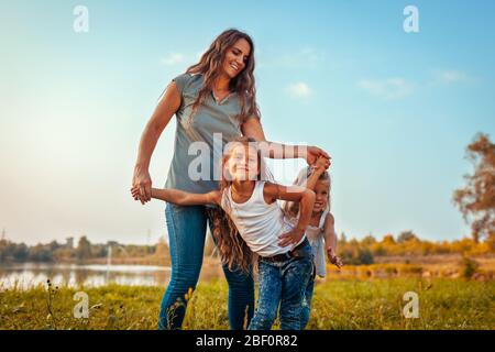 Giorno della madre. Famiglia divertirsi nel parco primaverile. Donna che ride e addolente con le figlie. Sorelle bambini che giocano Foto Stock