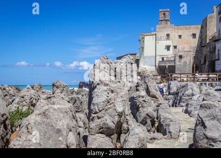 La costa rocciosa della città di Cefalu, situata sulla costa tirrenica della Sicilia, Italia - vista con la Chiesa Santa Maria dell'Itria Foto Stock