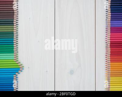 due file di matite colorate su sfondo di legno. vista dall'alto Foto Stock